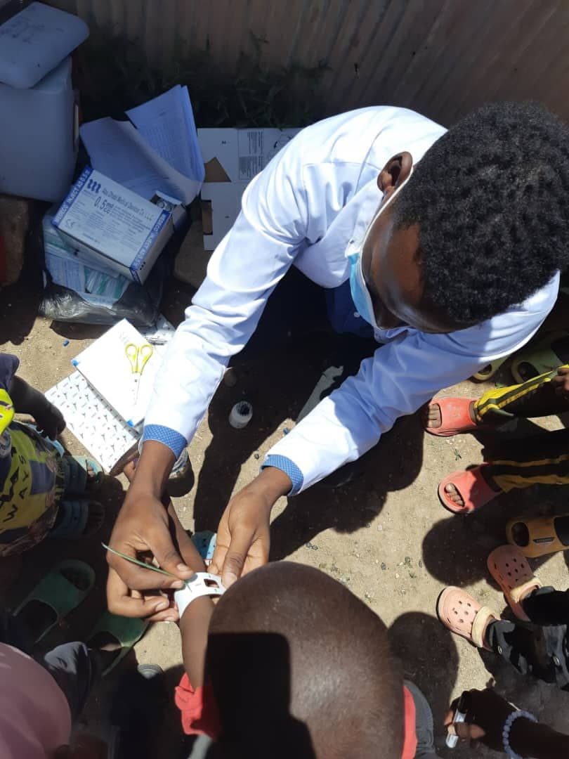 A SHIFA field health worker preparing a vaccine dose during an outdoor immunization campaign