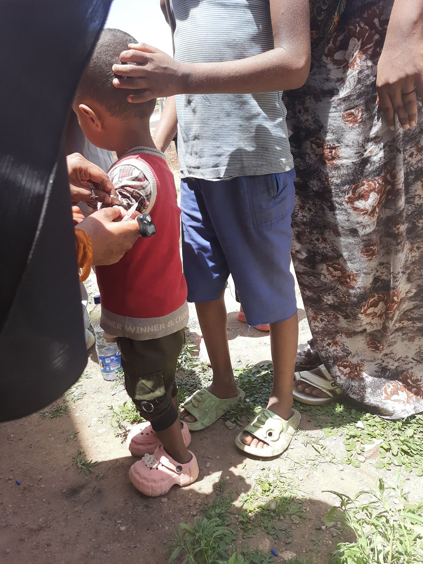 A SHIFA health worker administers a vaccine to a young child during a community immunization campaign